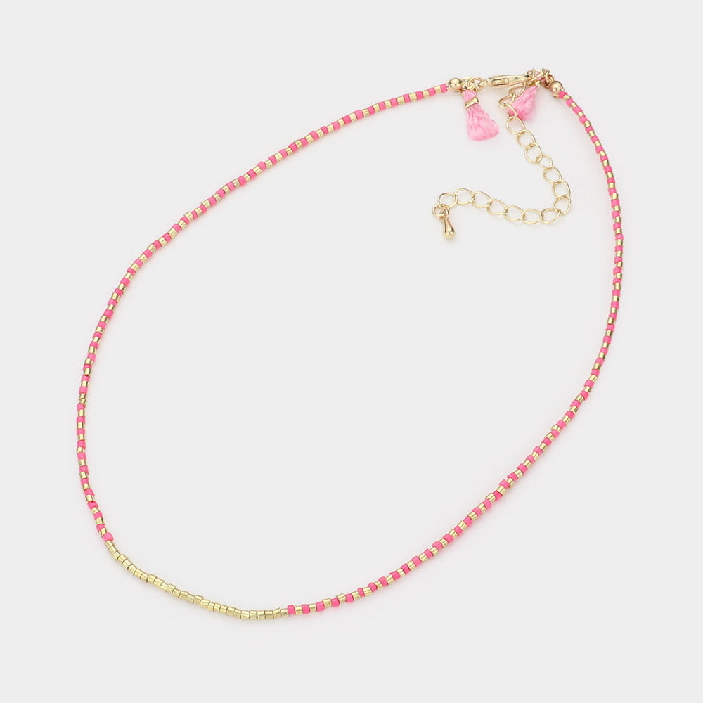 Necklace with pink and gold beads and heart charms on a light gray background