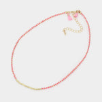 Necklace with pink and gold beads and heart charms on a light gray background
