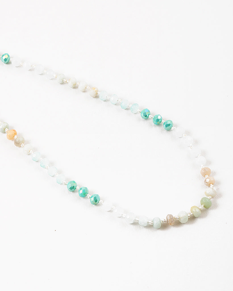 Necklace with alternating green, beige and white beads on a white background