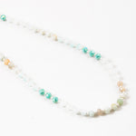 Necklace with alternating green, beige and white beads on a white background