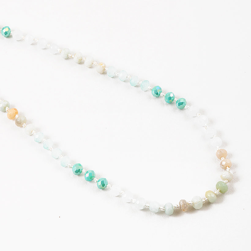 Necklace with alternating green, beige and white beads on a white background