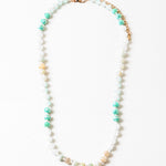 Necklace with beads in white, teal and beige on a white background