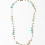 Necklace with beads in white, teal and beige on a white background