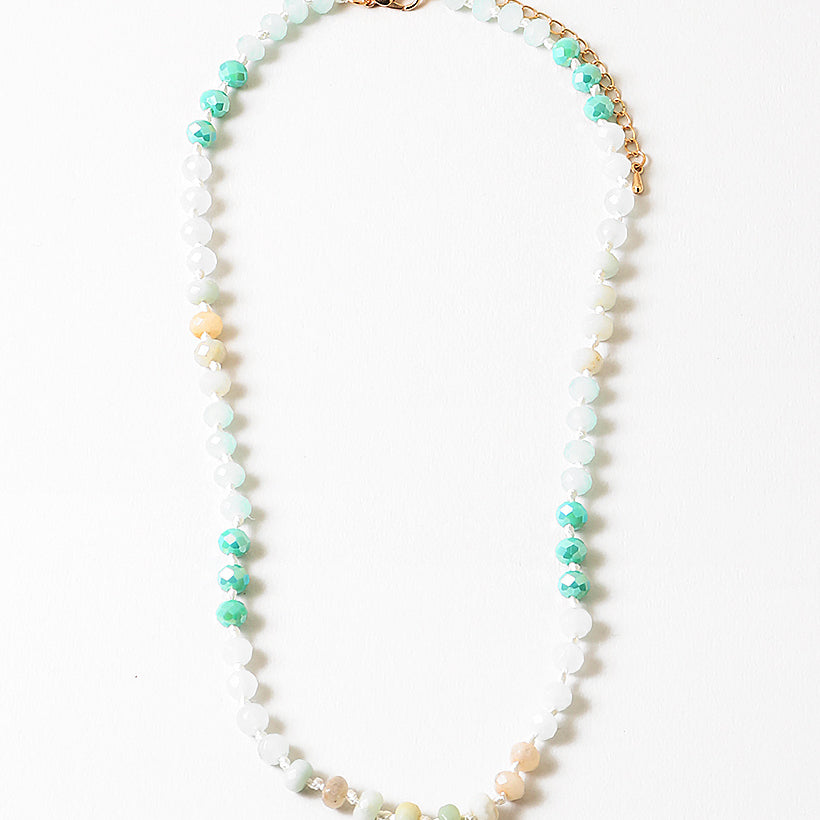 Necklace with beads in white, teal and beige on a white background