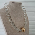 Chunky clear bead statement necklace with a large gold center bead.