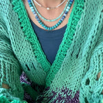 Picture of the front of a woman wearing a set of three bead necklaces. Necklace beads are blues and turquoise