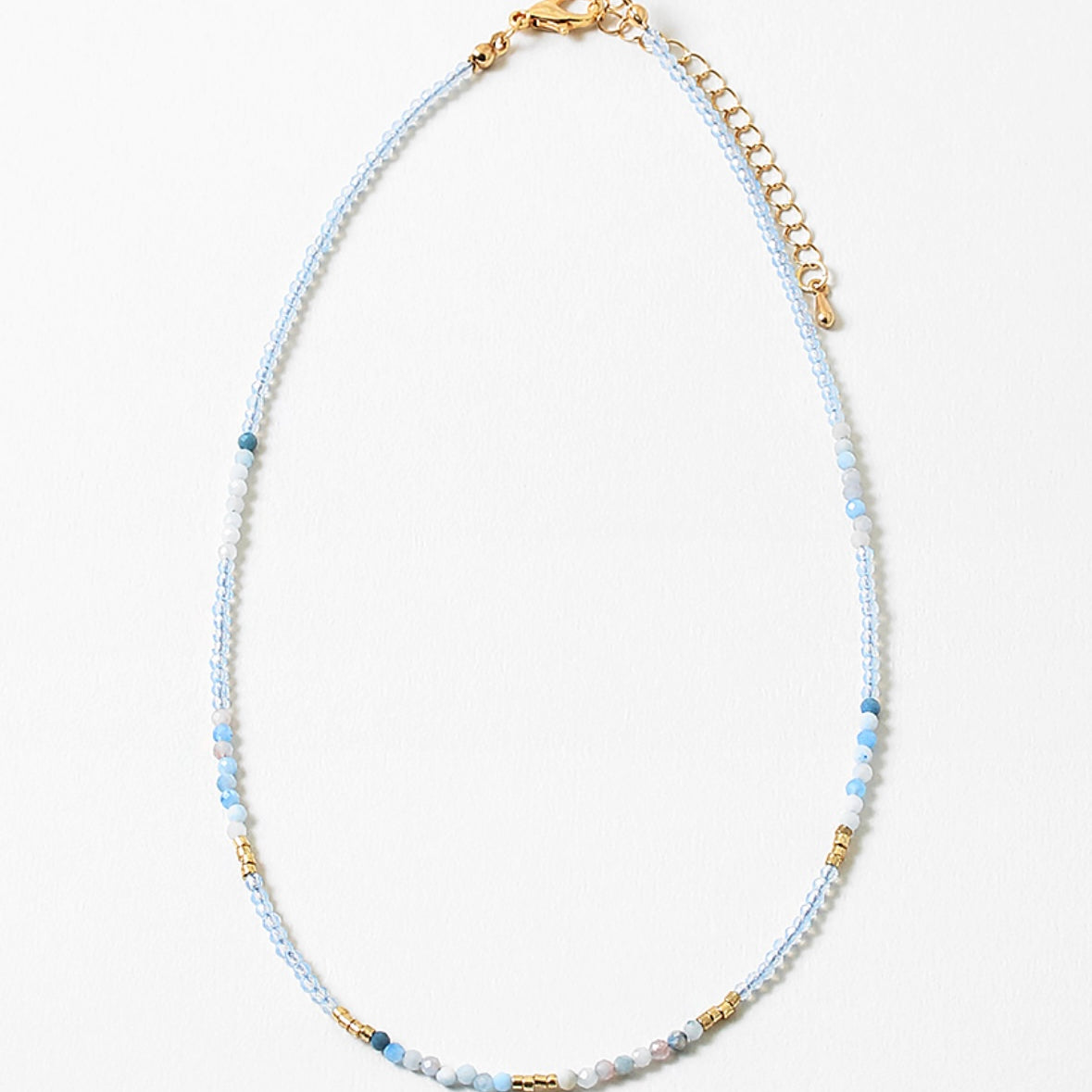 Dainty bead necklace with clear blue beads, gold and some solid blue beads.
