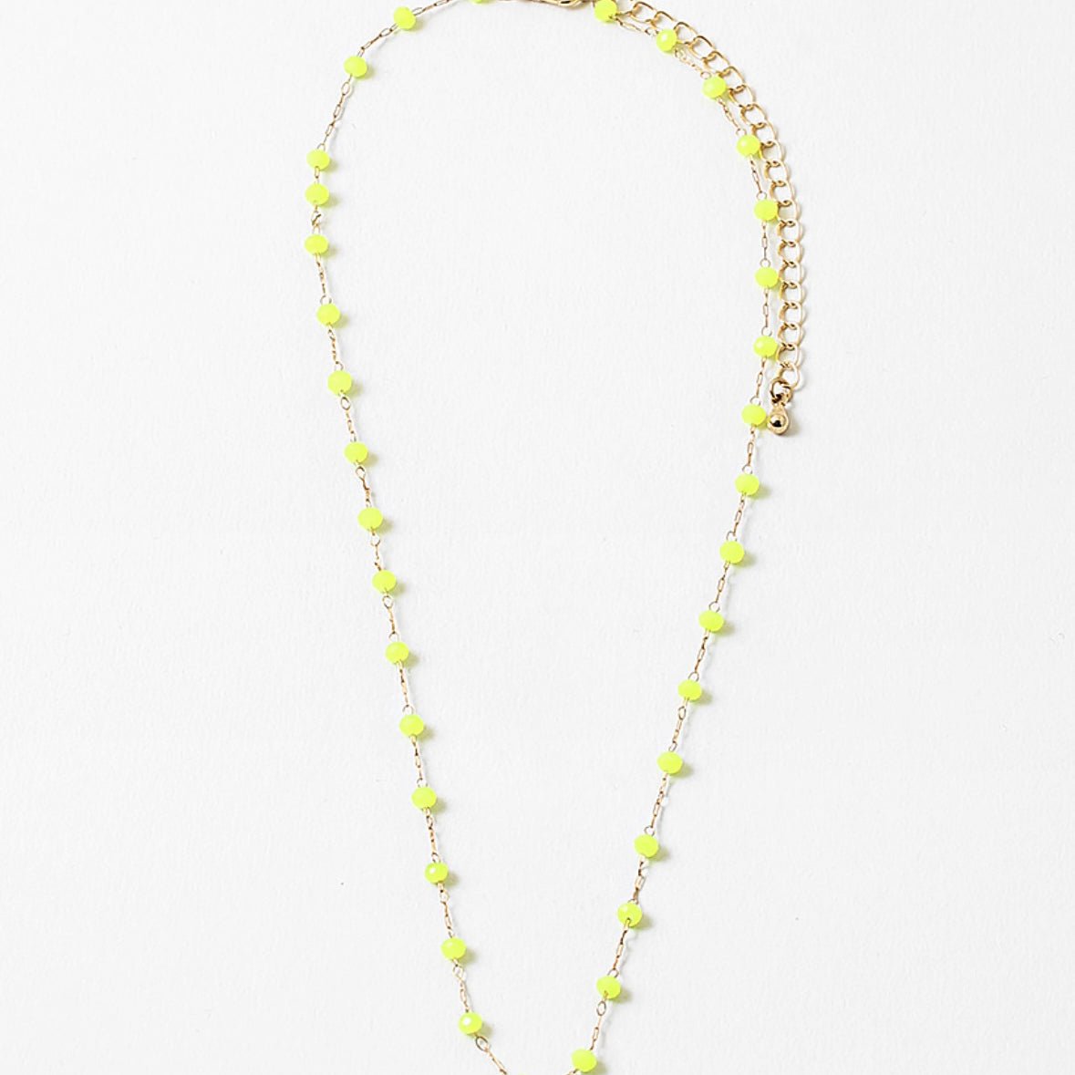 A gold-colored necklace with neon yellow beads and a clasp, displayed against a white background.