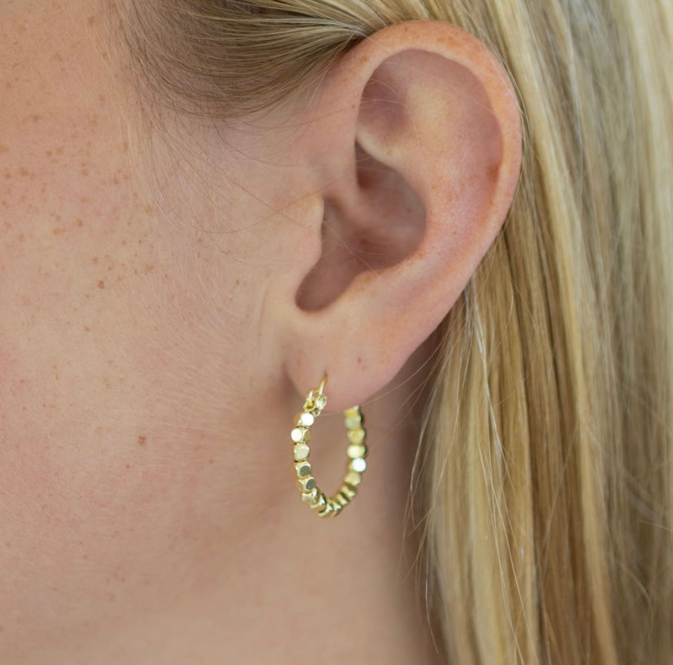 Gold hoop earring worn by a person with blonde hair.