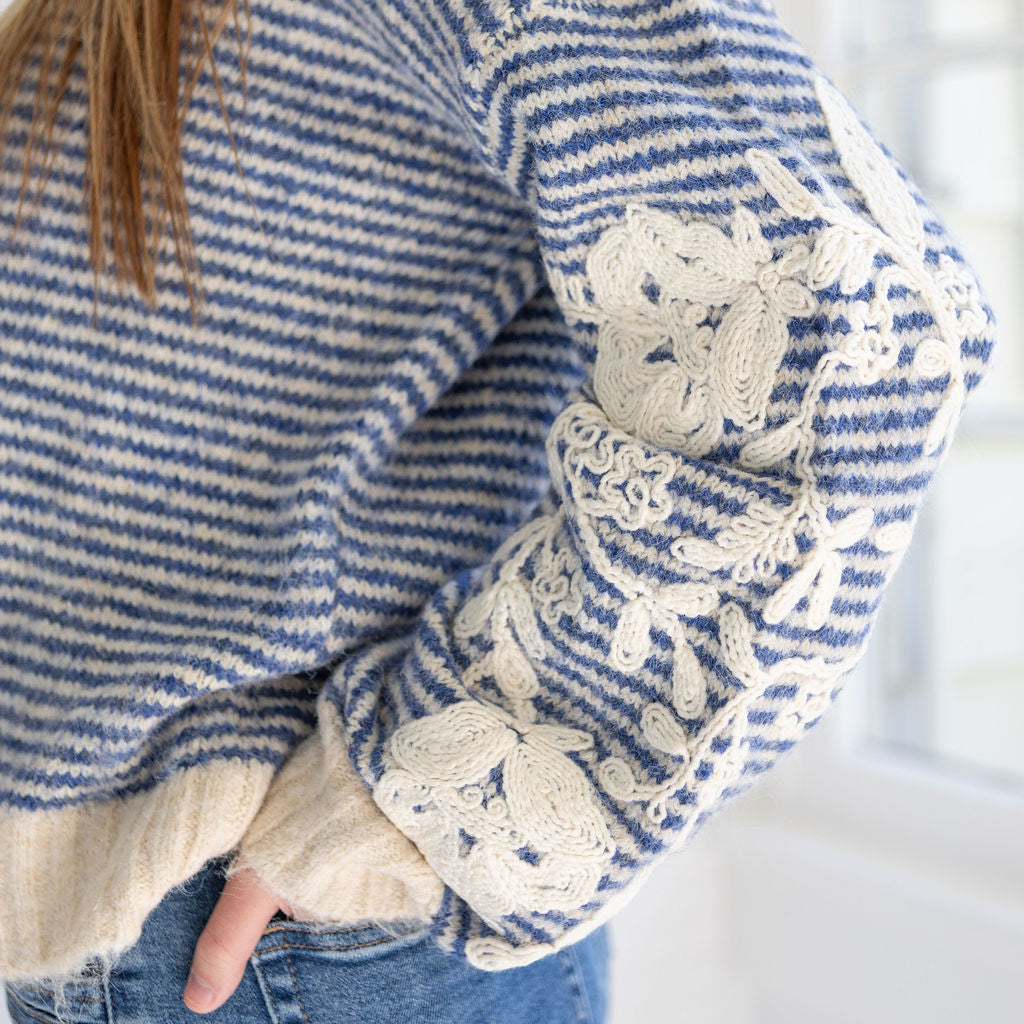 Blue and white striped sweater with lace details on cuffs and hem, worn by a person.