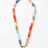 Brightly colored bead necklace with orange, yellow, blues and green beads. Necklace has a large gold clasp at its center.