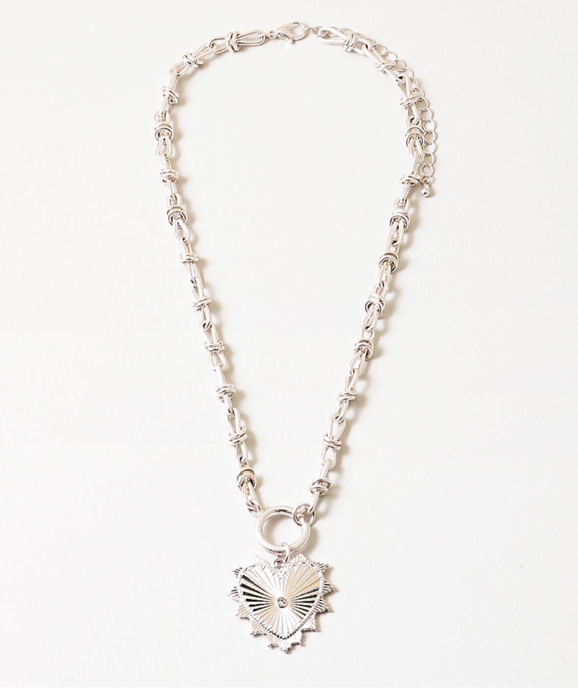 Silver necklace with a heart-shaped pendant on a white background