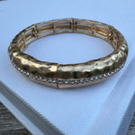 Gold cuff bracelet with a stripe of clear stones down the center.