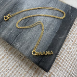 Picture of a fine gold chain necklace with a gold "MAMA" pendant hanging from it.