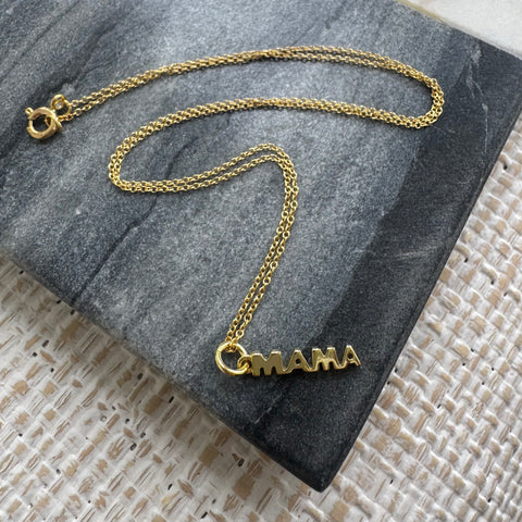 Picture of a fine gold chain necklace with a gold "MAMA" pendant hanging from it.