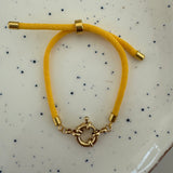 Yellow bracelet with gold clasp on a speckled surface
