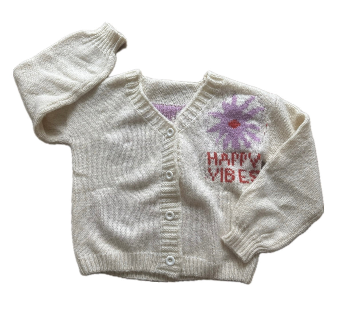 Picture of a cream colored sweater with a purple flower with a red center and red lettering that read, "Happy Vibes".