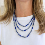 Picture of woman wearing a set of three layered necklaces made of dark blue beads.
