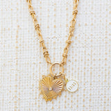 Picture of gold toggle chain with a large gold heart pendant with diamond in the center. Necklace has another white pendant that reads "11:11"