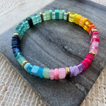 Picture of a multicolored rectangular beaded bracelet in clear and solid colors. Colors are greens, blues, pinks, purples and yellows.