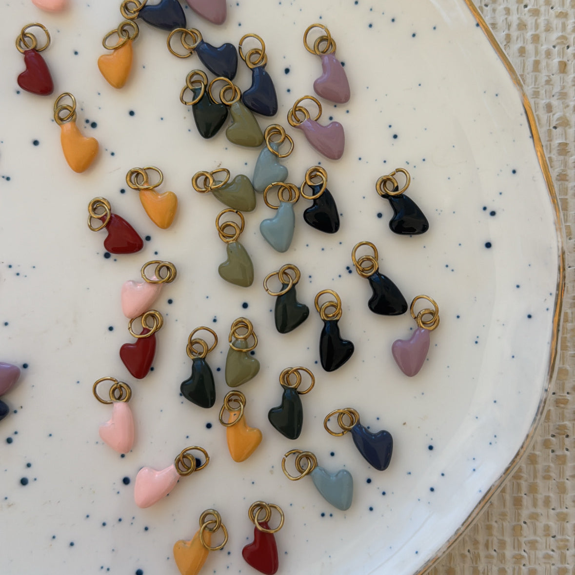 Assorted colorful heart-shaped charms on a speckled ceramic plate.