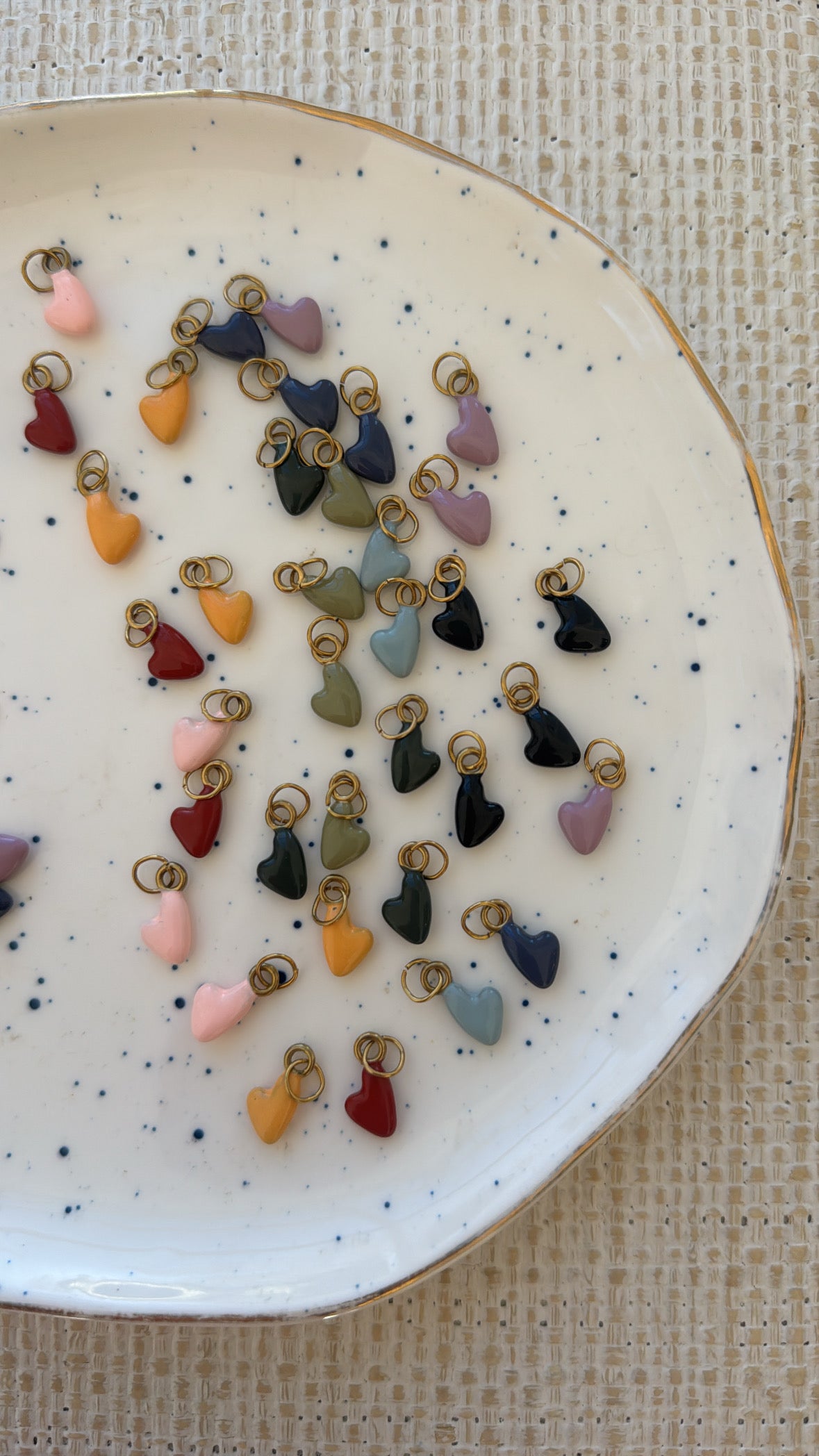 Assorted colorful heart-shaped charms on a speckled ceramic plate.