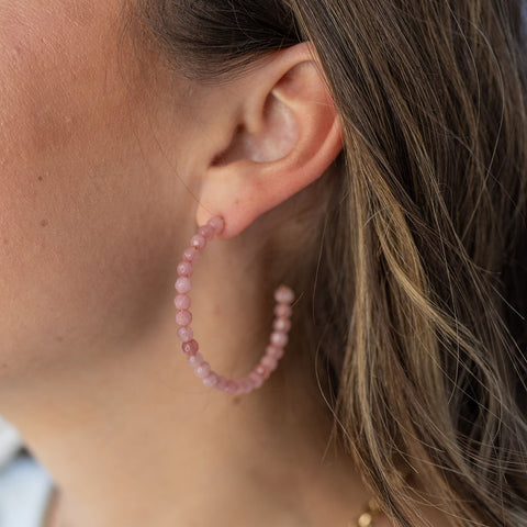 Model wearing rose colored beaded hoop earring