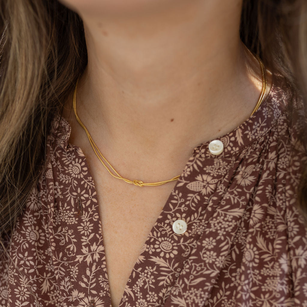 Model wearing dainty two strand necklace with a petite knot at the center