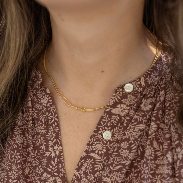 Model wearing dainty two strand necklace with a petite knot at the center