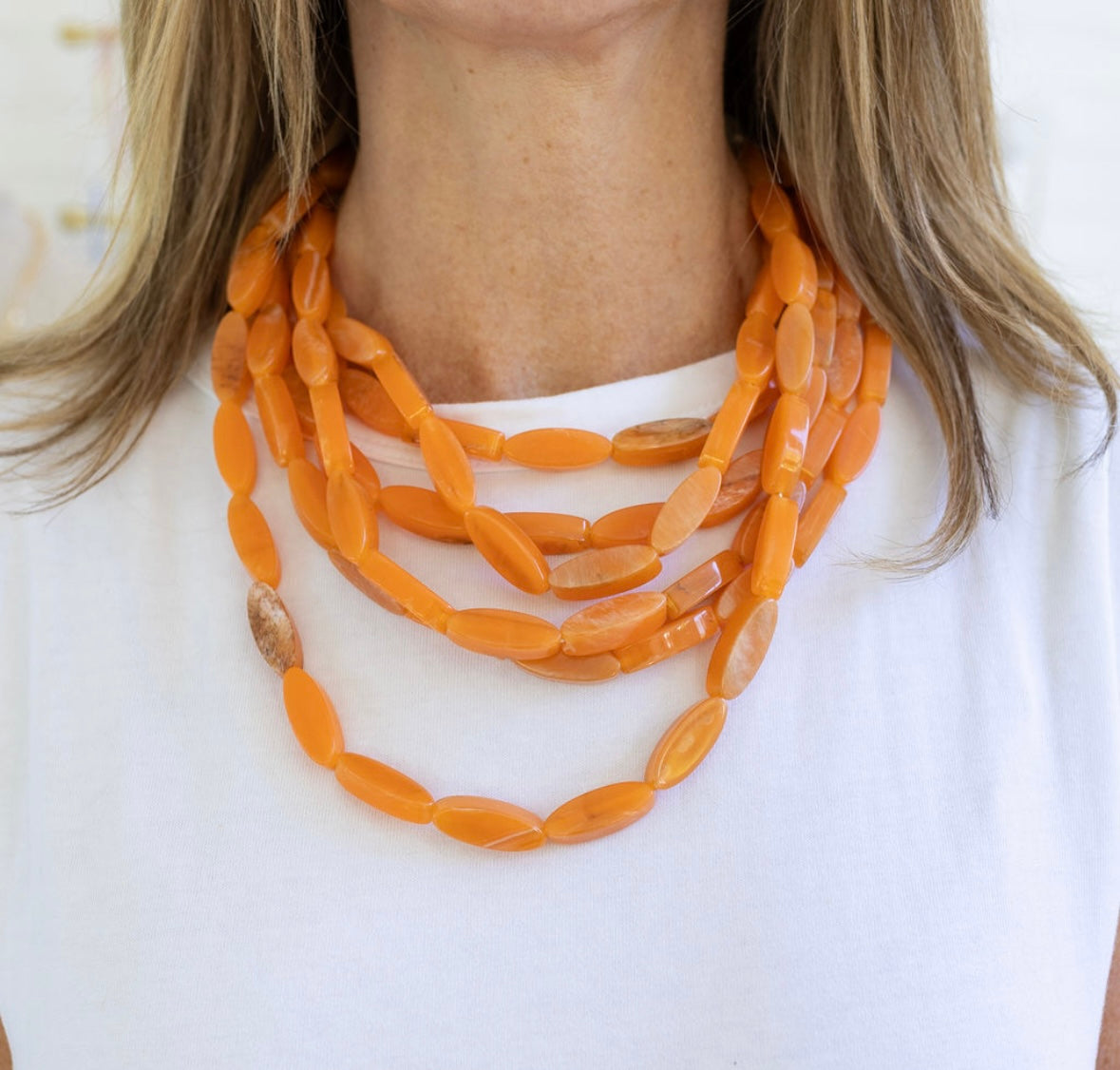 Orange necklace worn by a person on a white background