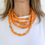 Orange necklace worn by a person on a white background