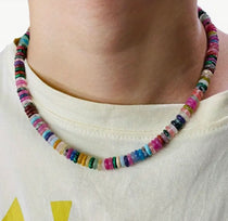Model wearing a short multicolored beaded necklace.