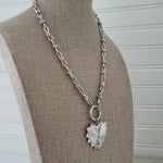 Silver large link toggle chain with a large textured heart pendant.