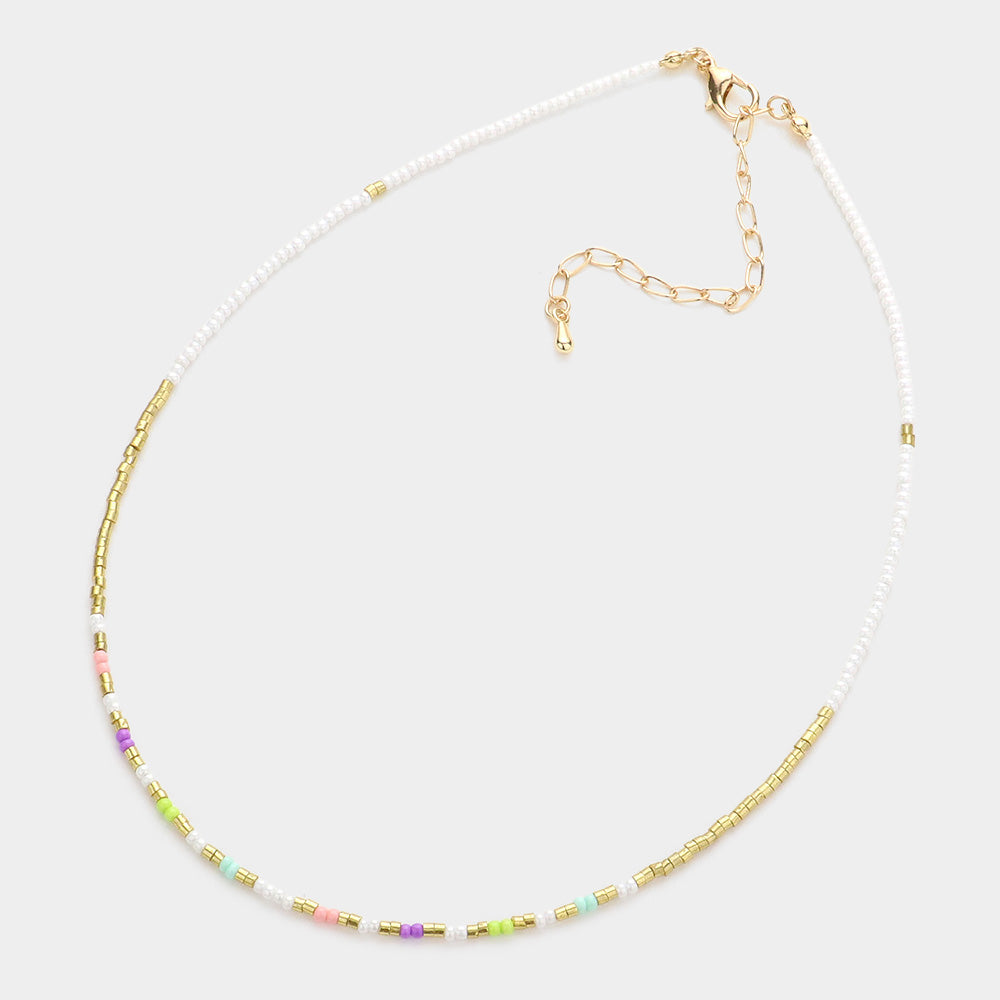 Necklace with small beads in white, green, purple and gold on a white background