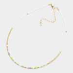 Necklace with small beads in white, green, purple and gold on a white background