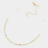 Necklace with small beads in white, green, purple and gold on a white background