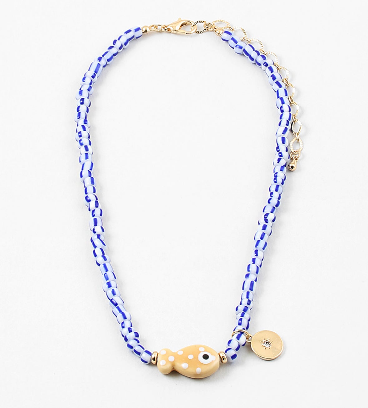 Picture of a bead necklace made of white and blue striped beads and a tan fish bead with a gold disc pendant.