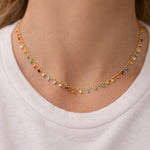 Dainty necklace with colorful beads worn by a person on a white background