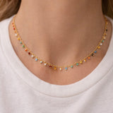 Dainty necklace with colorful beads worn by a person on a white background