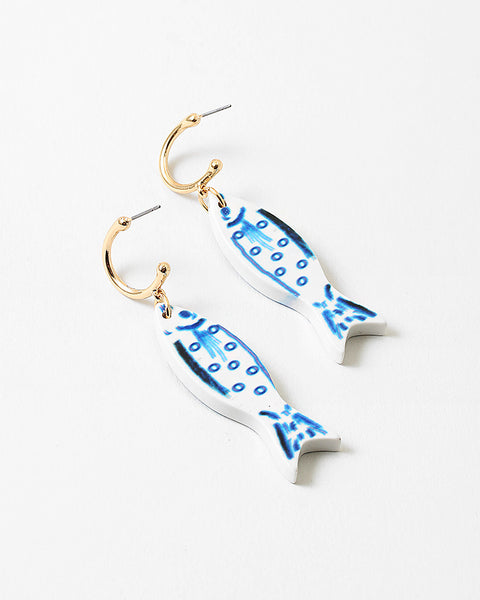 Picture of small gold hoops with white fish with blue details hanging from them.
