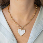 Picture of gold toggle chain with a large white heart pendant bordered by gold.