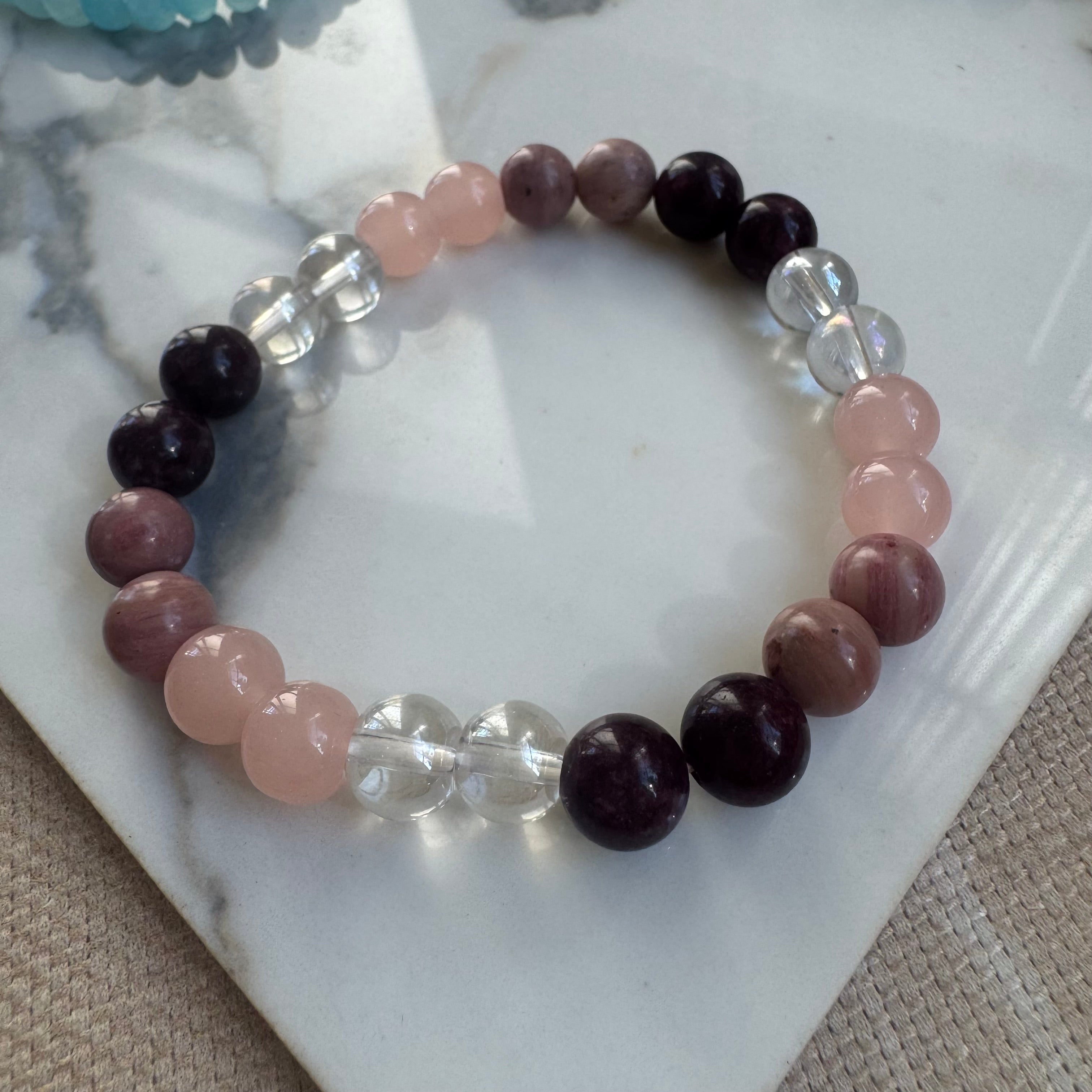 Beaded bracelet with pink, purple, and clear beads on a marble surface