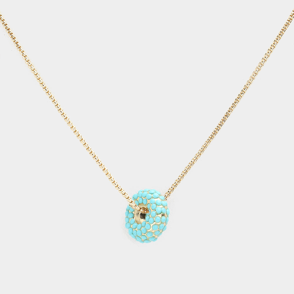 Turquoise donut shaped pendant necklace on a light background