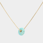 Turquoise donut shaped pendant necklace on a light background
