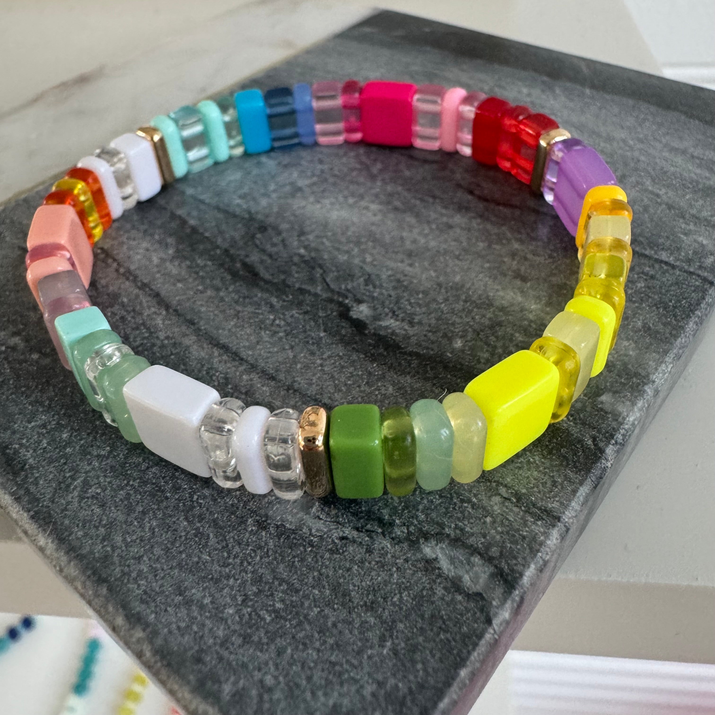 Picture of a colorful beaded bracelet in yellows, reds, purples, greens, whites and coral.