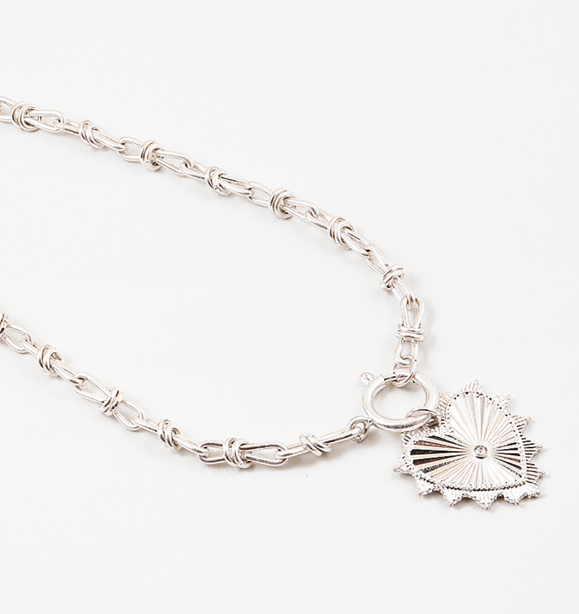 Silver necklace with a large heart charm on a white background