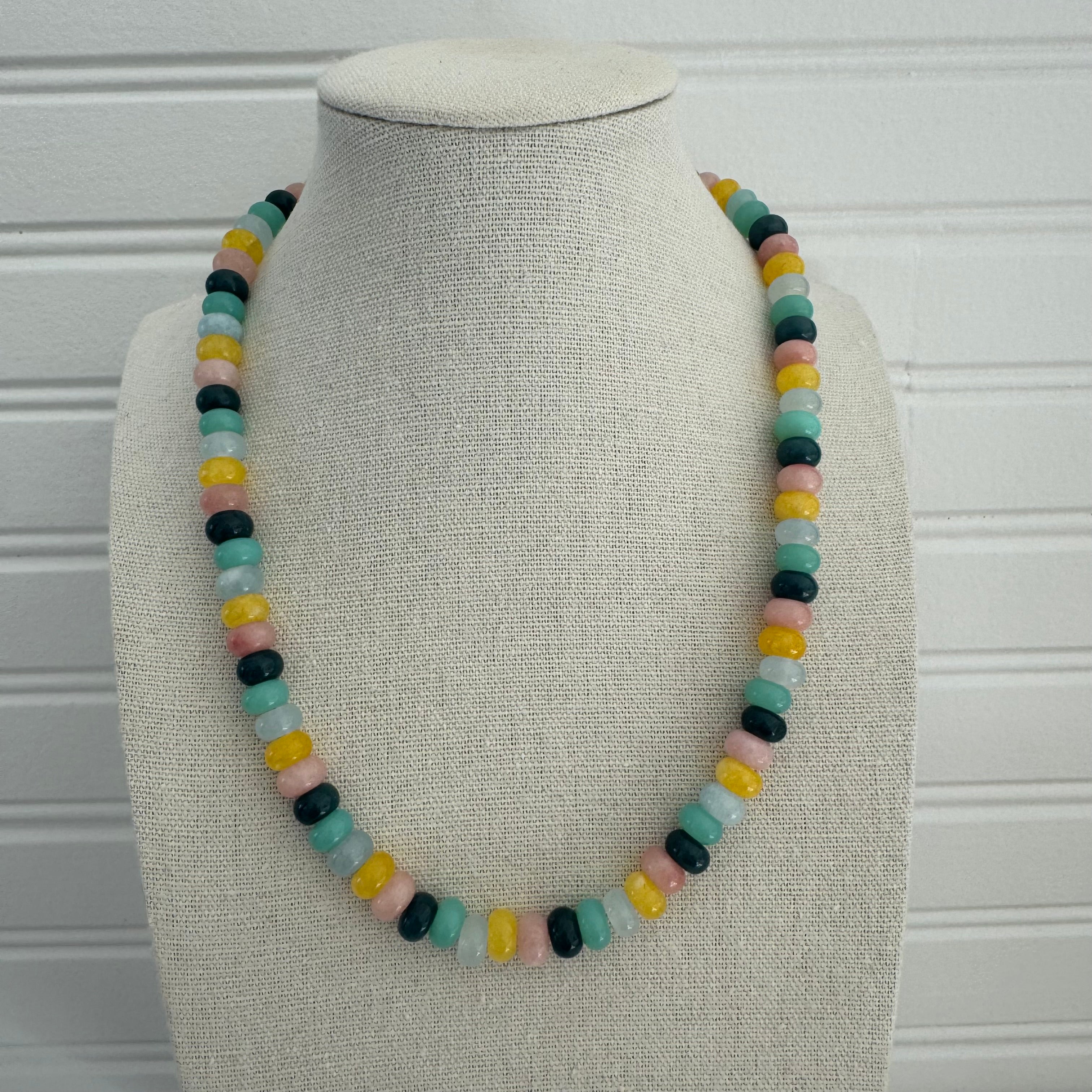 Picture of a necklace made of green, blue, white, yellow and pink beads with a large gold carabiner clasp.