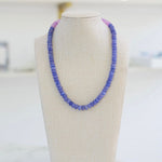 Picture of a blue resin bead necklace with a section of purple beads.