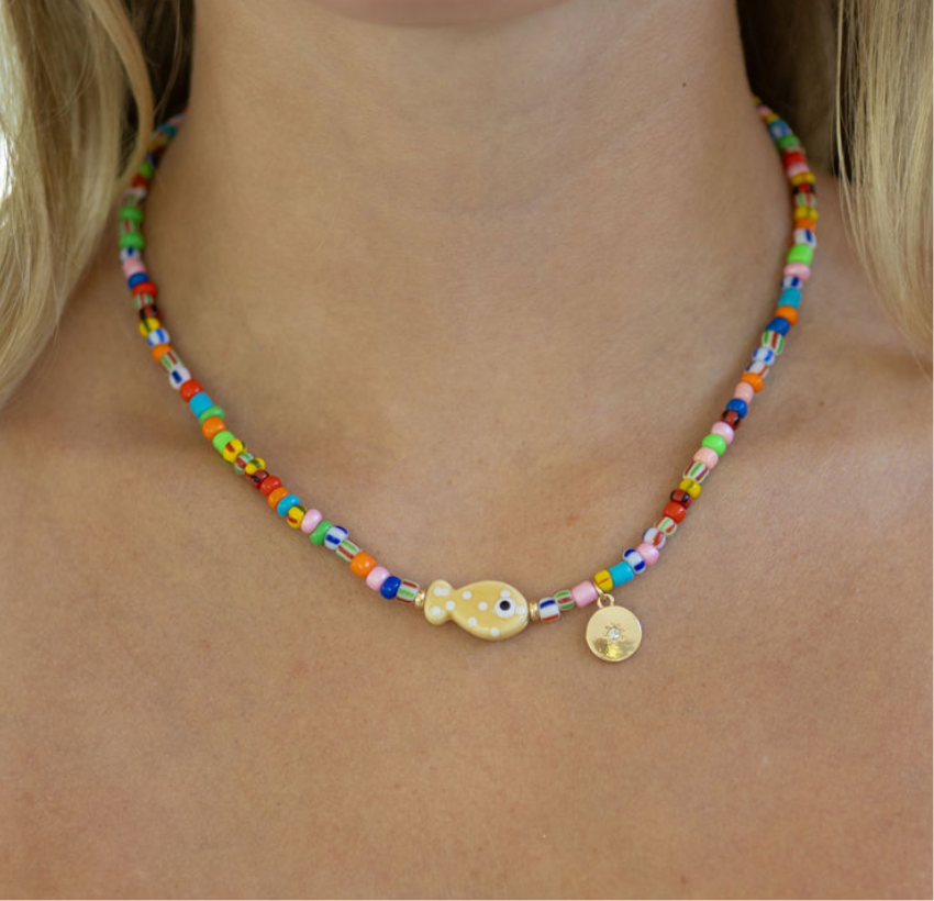 Multicolor bead necklace with a central fish pendant and gold disc pendant.