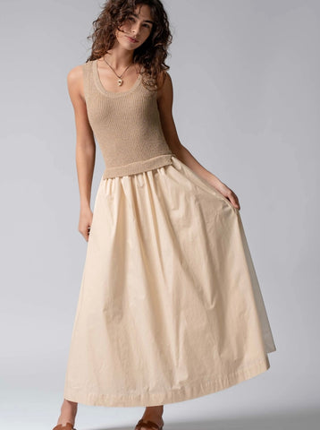 Woman wearing a beige sleeveless top and skirt on a plain background